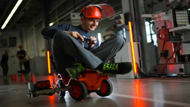 Een groep medewerkers tilt een andere medewerker op die in het zonnetje wordt gezet en daarvan geniet. 