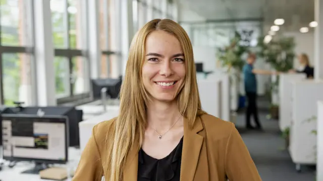 Een groep medewerkers tilt een andere medewerker op die in het zonnetje wordt gezet en daarvan geniet. 